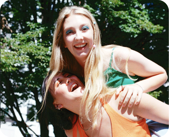 a girl giving another girl a piggy back while laughing